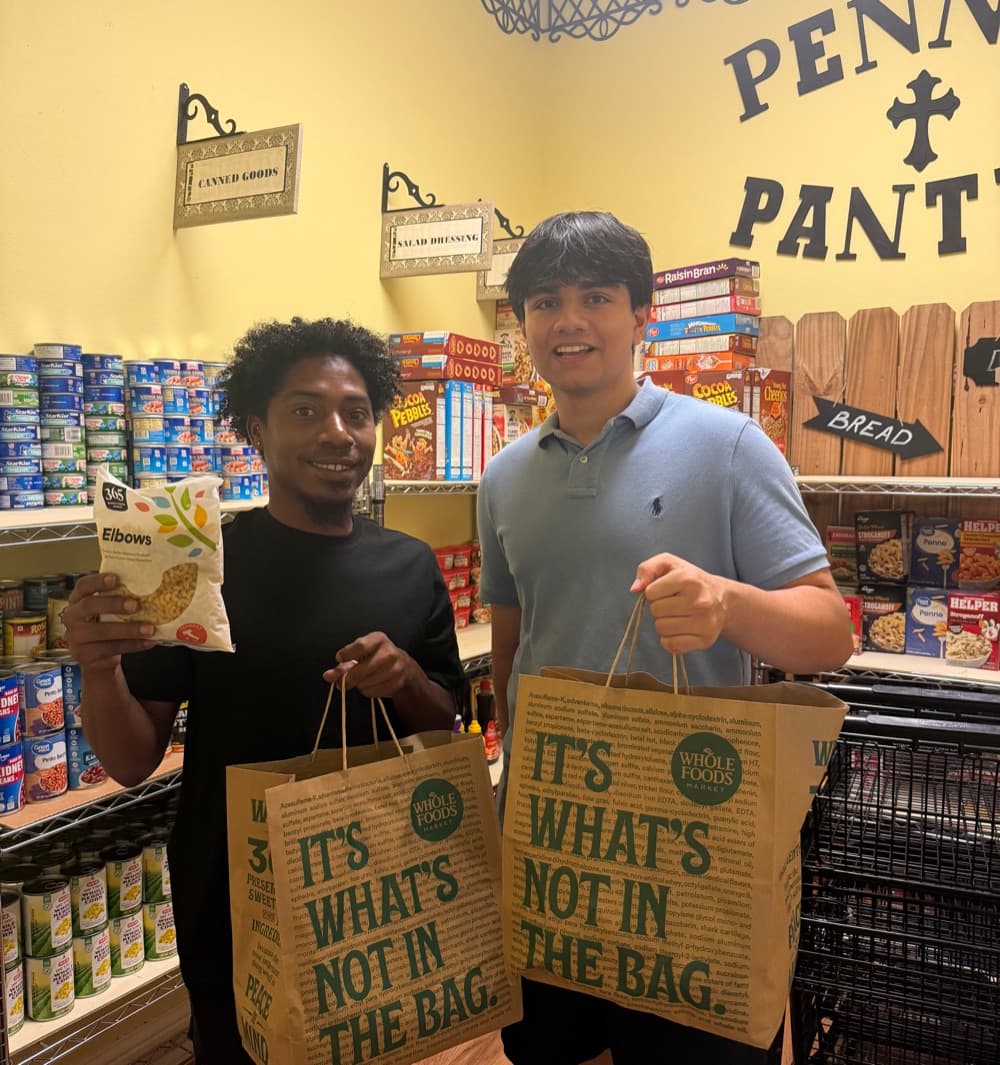 Sid Sharma and a volunteer holding Whole Foods bags of rescued groceries in the Fort Bend Family Promise pantry